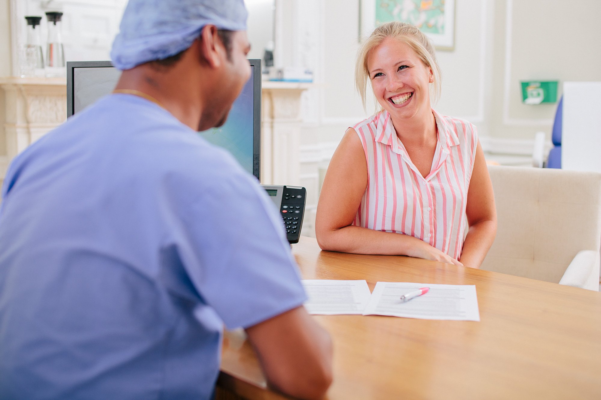 Male fertility doctor dressed ins crubs, looking at a patient, both smiling.
