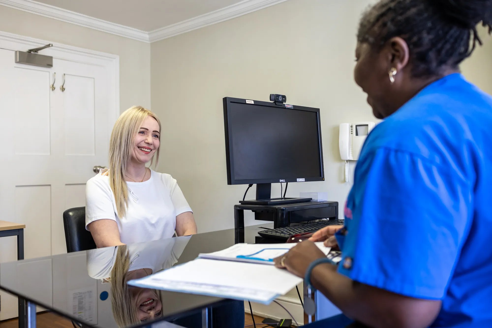 Fertility Nurse in scrubs looking through a file and talking to a patient.