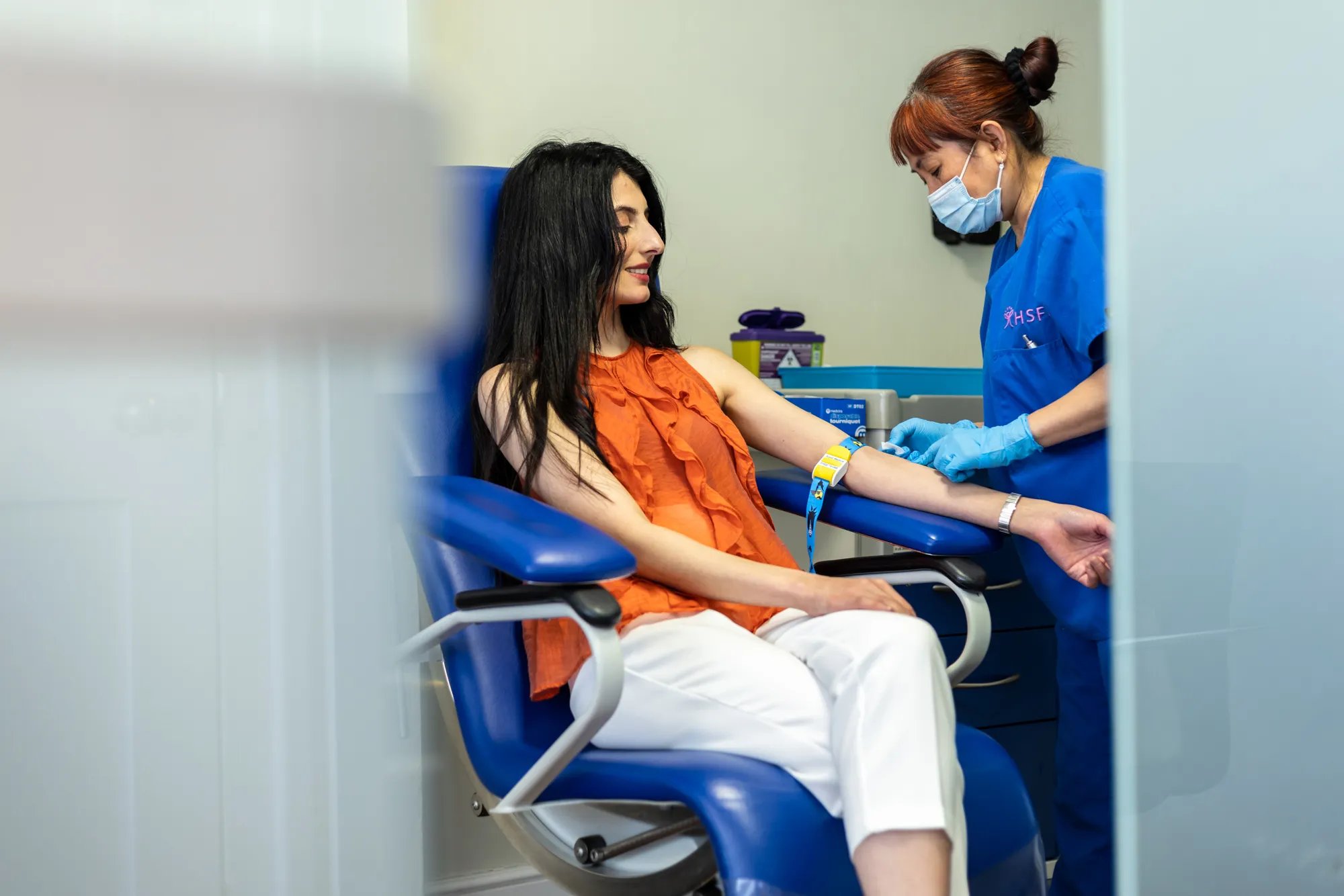 NUrse dressed in scrubs, taking blood from an IVF patient. 