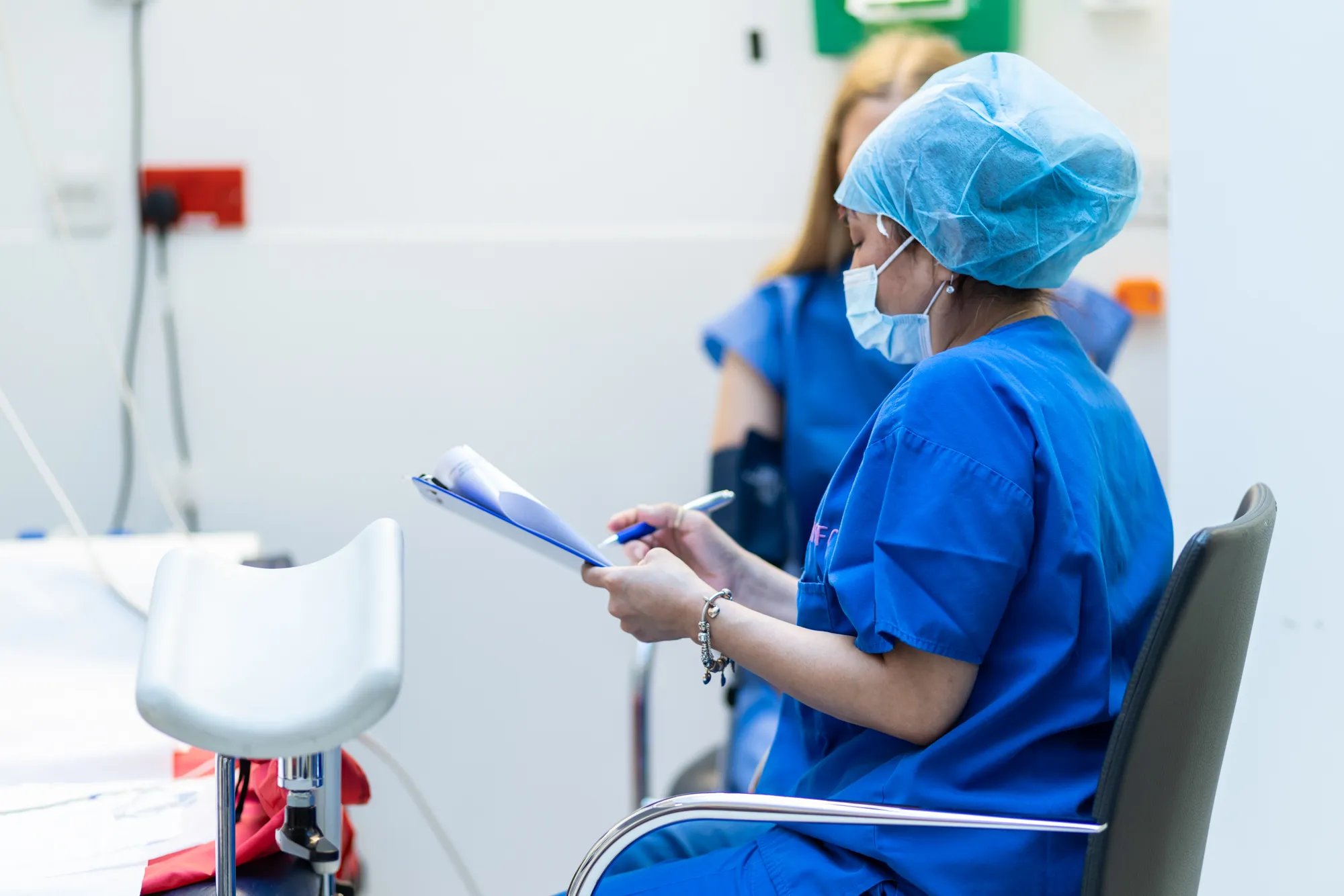 nurse wearing scrubs, reading from a file.