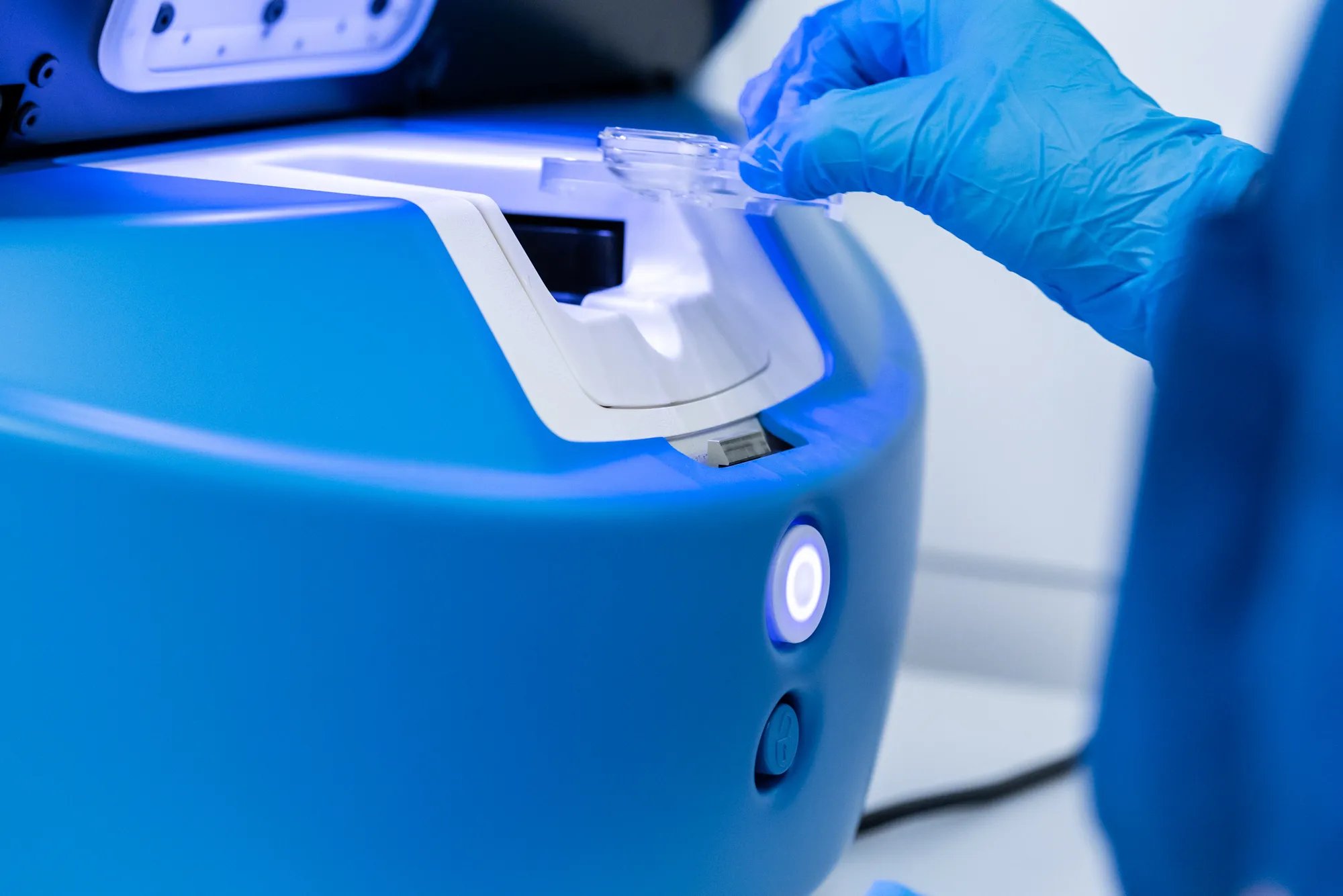 An embryologist's gloved hand adding a sample in an incubator. 